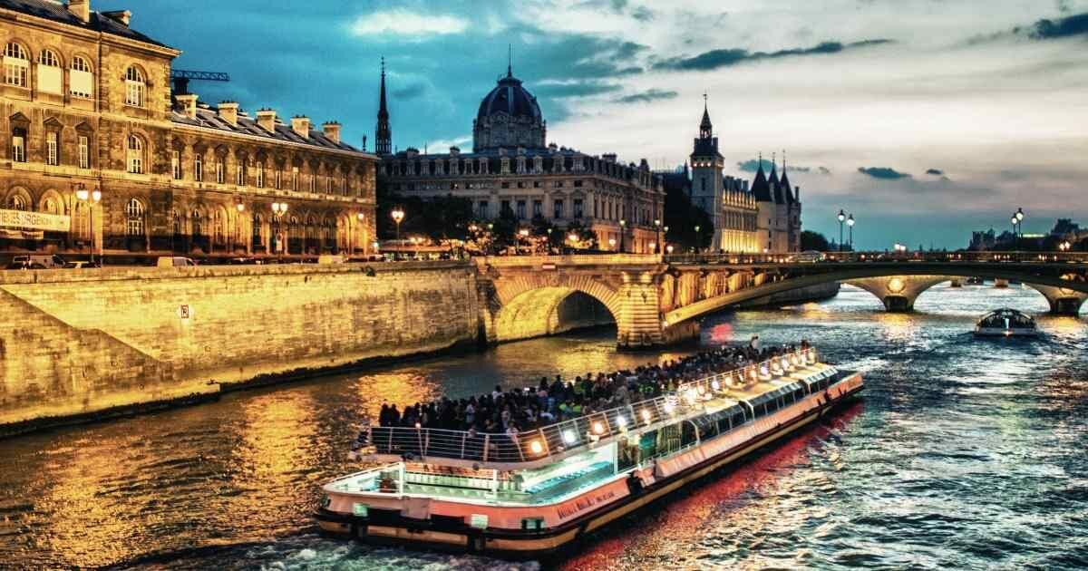 European river cruise with passengers passing through city 