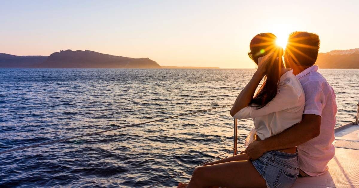 newlyweds on a boat looking out at sunset 